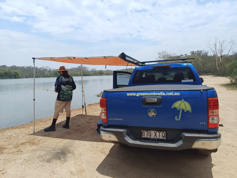 Blue Green Umbrella ute with man standing next to it fishing