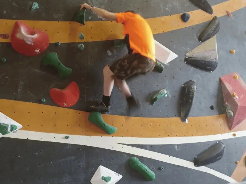 Man wearing orange shirt rock climbing