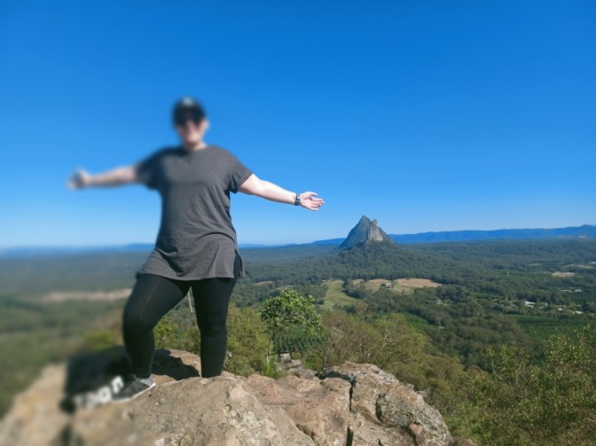 Happy woman standing on cliff with arms open