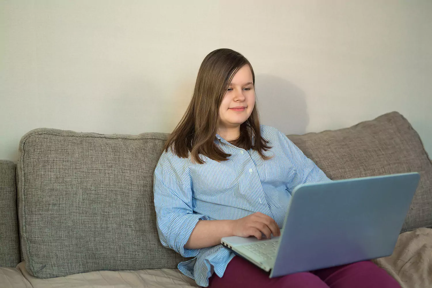 Woman sitting on couch using laptop to make an NDIS referral